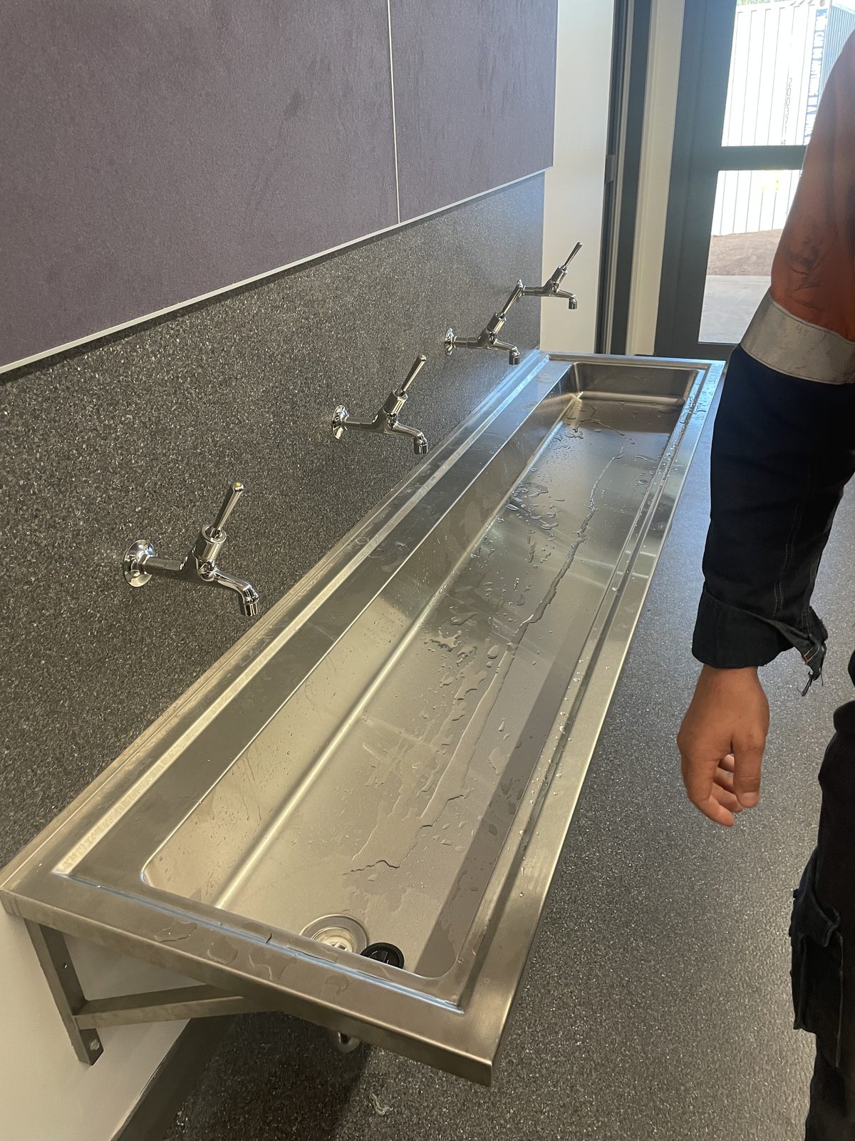 Stainless steel hand wash trough installed in a commercial fit-out