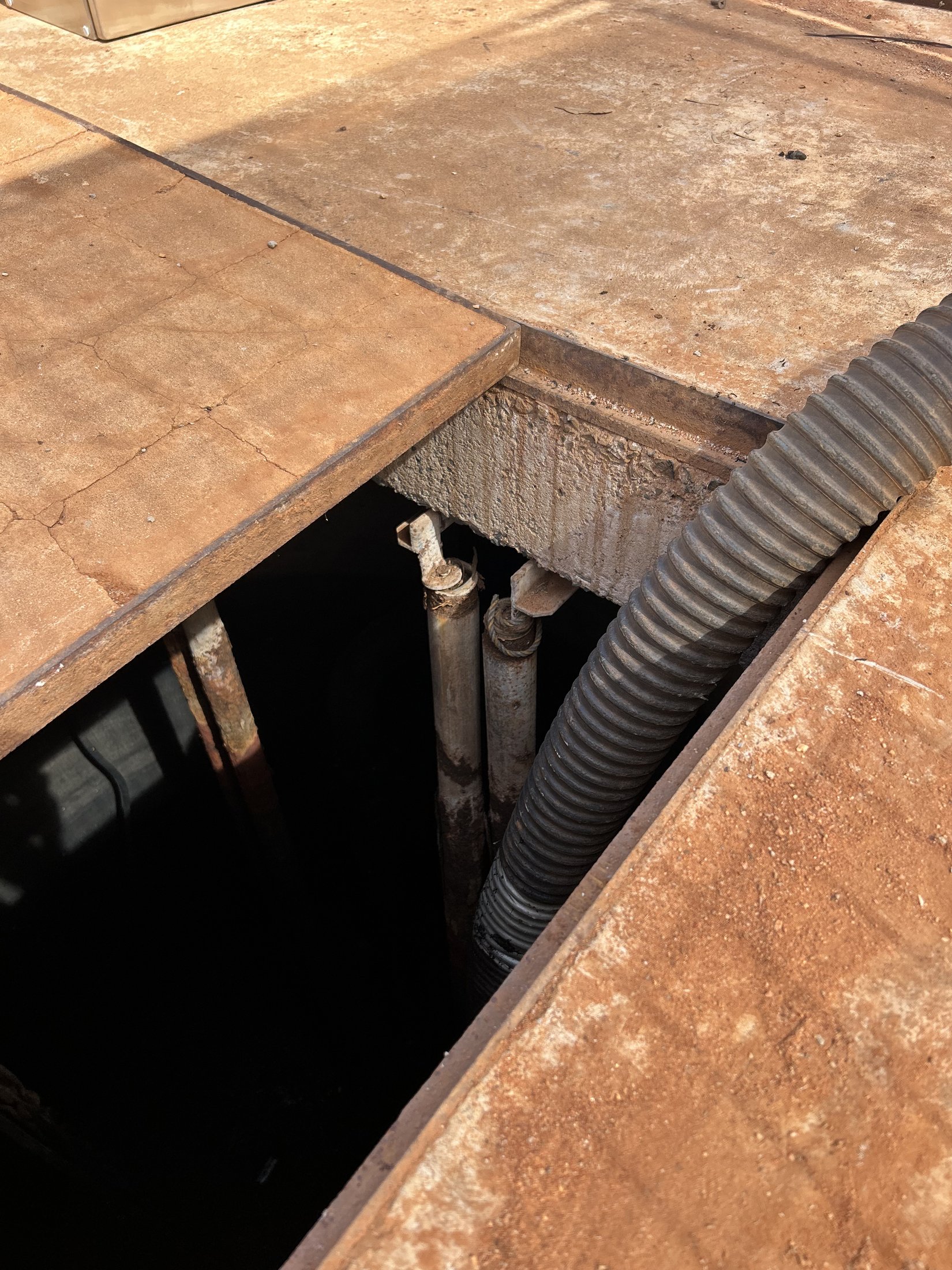 Pump station access pit with plated cover and service penetrations